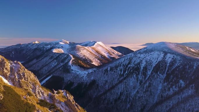 五彩斑斓的雪山在寒冷的冬日清晨的大自然中俯瞰着空中风景.和游客一起在岩石山顶上远足.倒飞显示无人机图