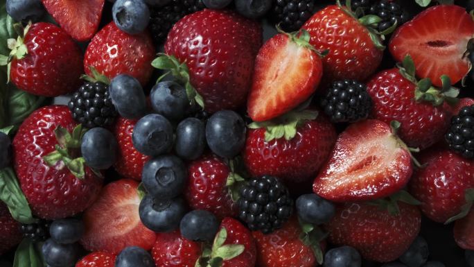 黑色背景的野生森林浆果，草莓、蓝莓和黑莓的集合.