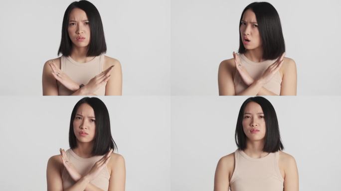 严肃的亚洲女孩，满脸怒容，没有任何姿势，双手交叉放在白色背景的相机上