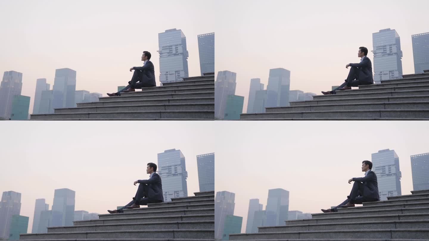 亚洲商人在现代城市日落时坐在台阶上的侧视图
