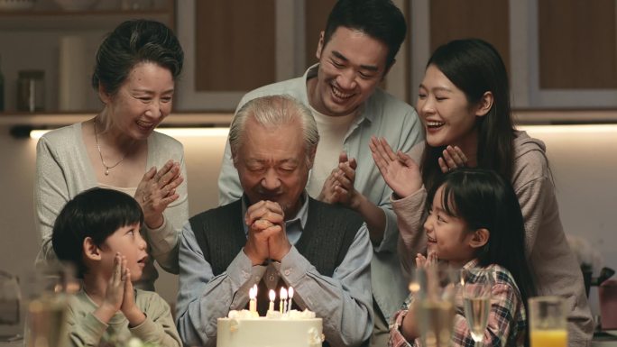 亚洲三代家庭在家用蛋糕和蜡烛灯庆祝爷爷生日