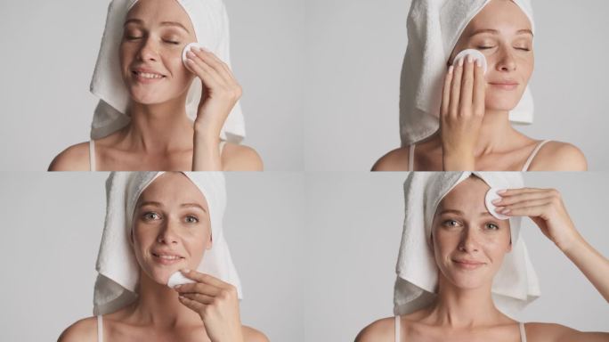 漂亮的姑娘，头戴毛巾，用棉质海绵在灰蒙蒙的背景下洗脸