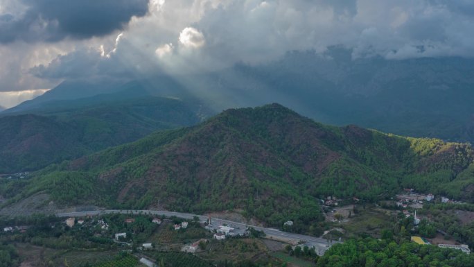 无人机视频镜头。在山脚下的住宅区上空飞行.绿树。高速公路。穿过灰蒙蒙的云彩高质量的镜头