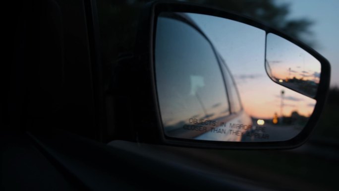 汽车后视镜中日落的倒影.开车旅行。汽车后视镜.