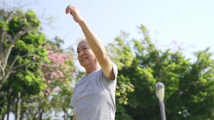 快乐的亚洲老人在公园里伸展双臂
