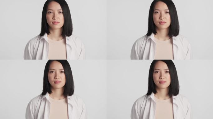年轻的亚洲女人的肖像，专注地看着相机在白色的背景。面部表情