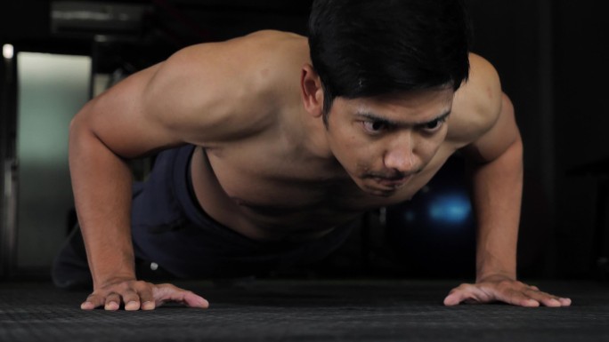 英俊的年轻亚洲肌肉运动员做俯卧撑在健身房，60fps
