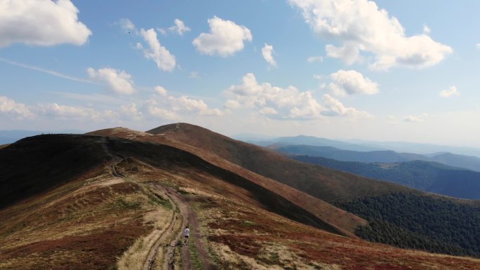 从空中俯瞰着年轻的军人，他们坐着山脊和背景上美丽的云朵跑到山顶