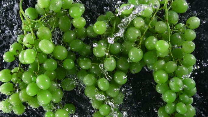 超慢速运动的新鲜绿色葡萄酒在绿色背景下以1000 fps的速度落水。用高速电影摄影机拍摄。