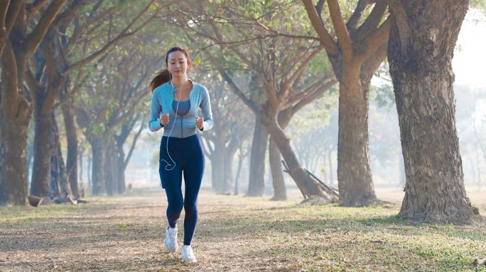 美丽的年轻女子早上在公园里奔跑