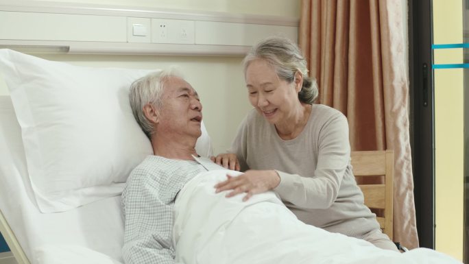 亚洲老年妇女在医院拜访丈夫，与丈夫聊天，亲吻额头