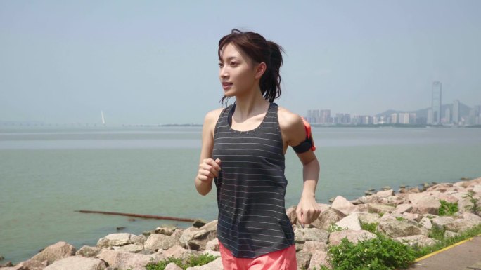 年轻的亚洲女人在海滨公园跑步