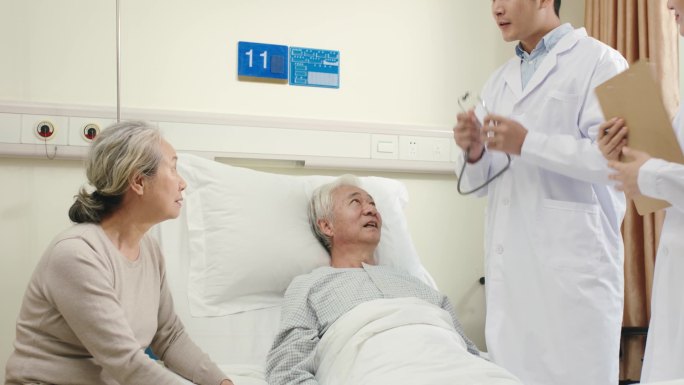 两名年轻的亚洲医生检查老年病人，并告诉他他的病情