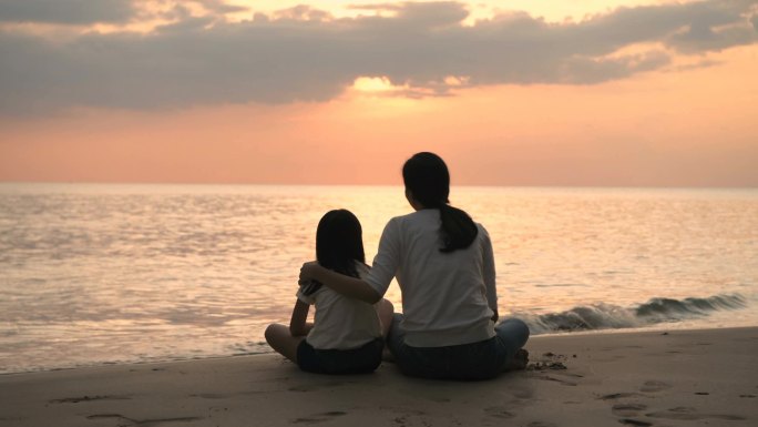 假期的概念。 母亲和女儿正在海滩上观看日落. 分辨率.