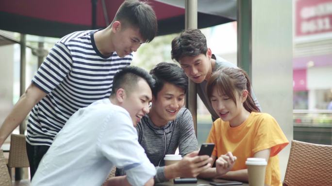 五个年轻的亚洲成年人组成的小组用手机浏览社交媒体信息