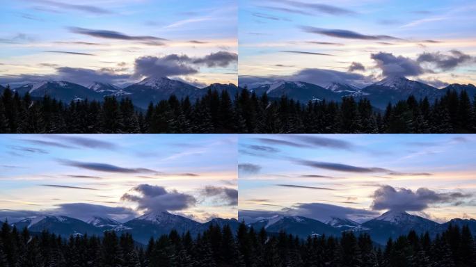 黄昏时,云彩在山上形成.前面被雪覆盖着的树木。多彩的天空