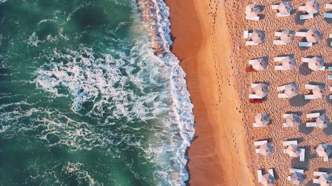 海洋海滩海岸的航拍视频，遮阳伞和躺椅，巨浪冲刷海沙