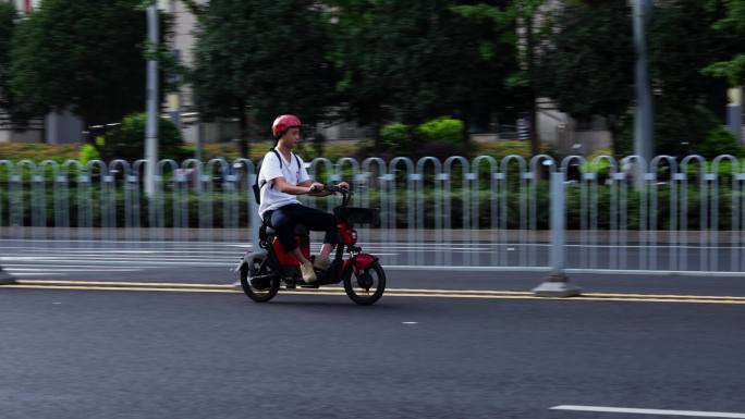 城市道路骑共享电单车飞驰的男孩