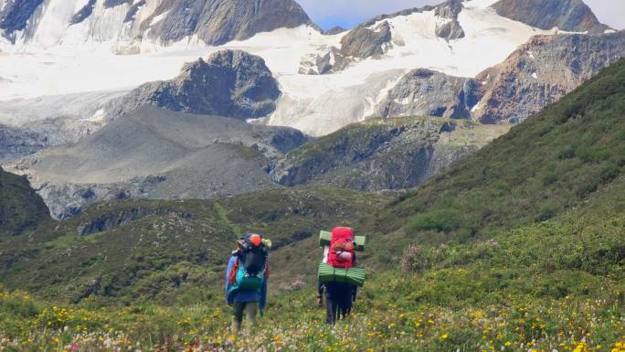 攀登阿沙贡格雪山的登山者徒步行走在花海中