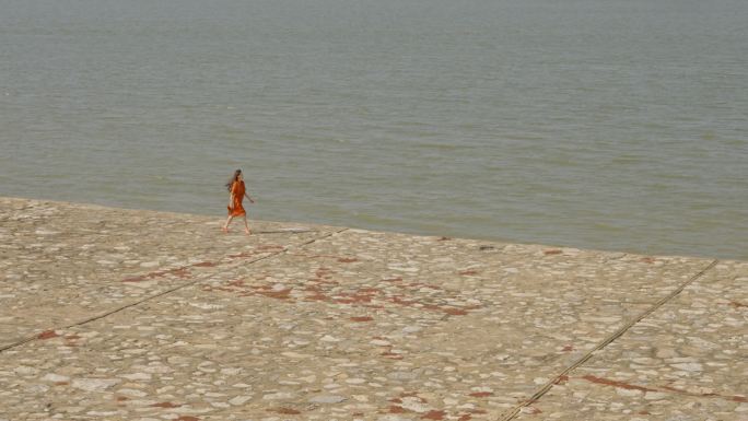 年轻女孩海边漫步享受生活海边吹风走动