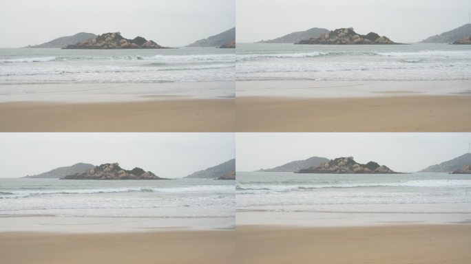 海浪涌上沙滩，远处的山依稀可见