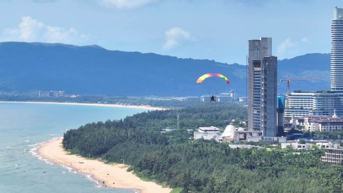 蓝天白云下动力伞沿着三亚海棠湾海岸线飞行