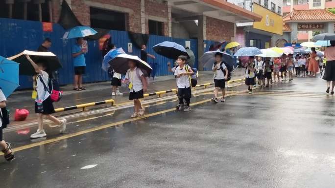 阴雨天小学生雨伞背书包排队放学路人行人