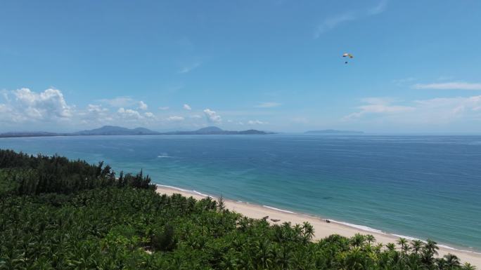 航拍三亚海棠湾蓝天白云动力伞沿海岸线飞行