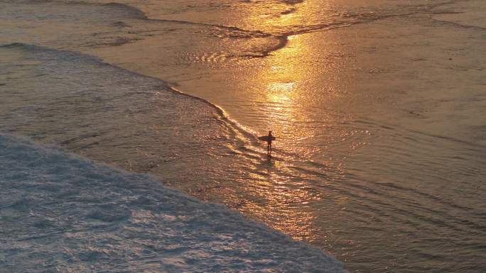 夕阳下抱着冲浪板的少年剪影