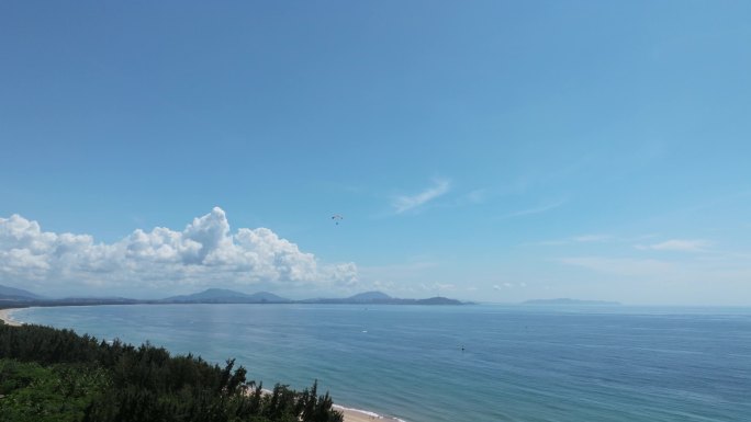 航拍蓝天白云下三亚海棠湾动力伞飞行及沙滩