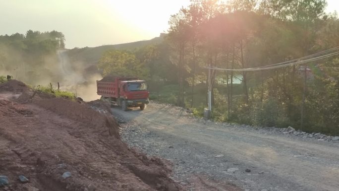 夕阳工地山路逆光灰尘泥头车爬坡尘埃飞扬