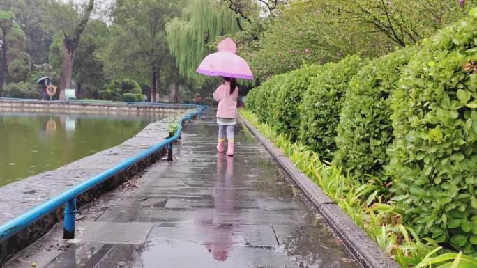 实拍城市公园小女孩走过下雨天打伞跳水坑