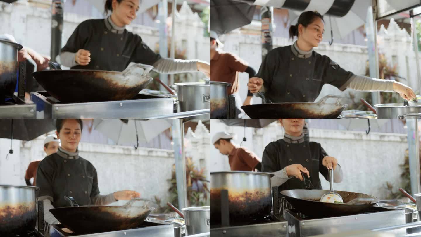 在曼谷市场，一位亚洲女厨师正在烹饪一种著名的泰国街头小吃——泰式炒粉。