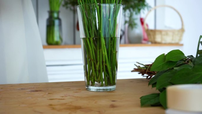 花商把玫瑰花加水放进花瓶里。茎部特写。