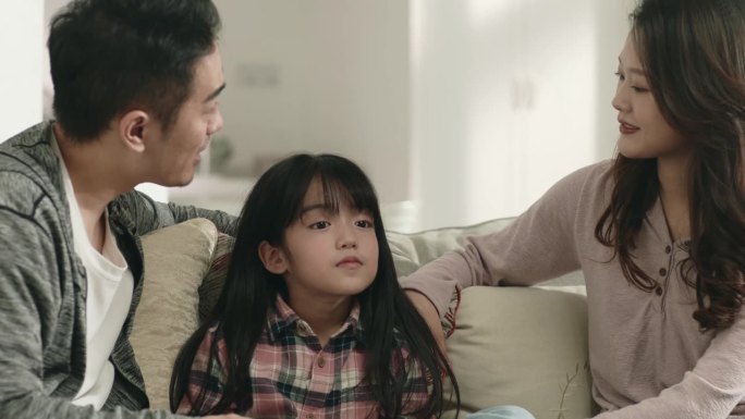 年轻的亚洲夫妇和女儿在家里聊天