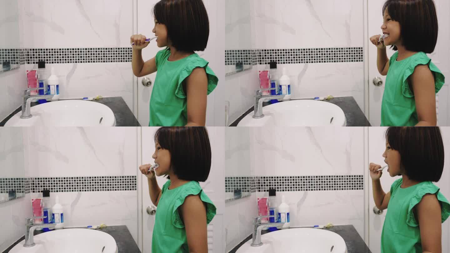 小女孩在浴室的水池边刷牙。