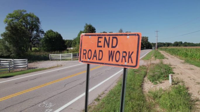 结束道路工程，在农村道路和田地旁边有黑色文字的橙色标志