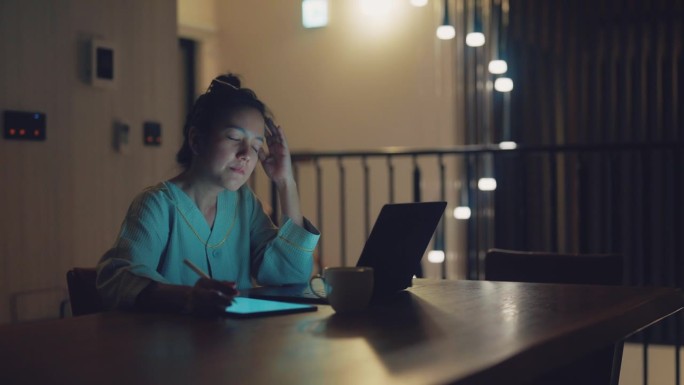 压力大的亚洲女商人在家用平板电脑远程工作时头痛和眼睛疲劳。
