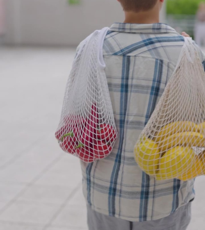 十几岁的男孩用可重复使用的购物袋把杂货带回家