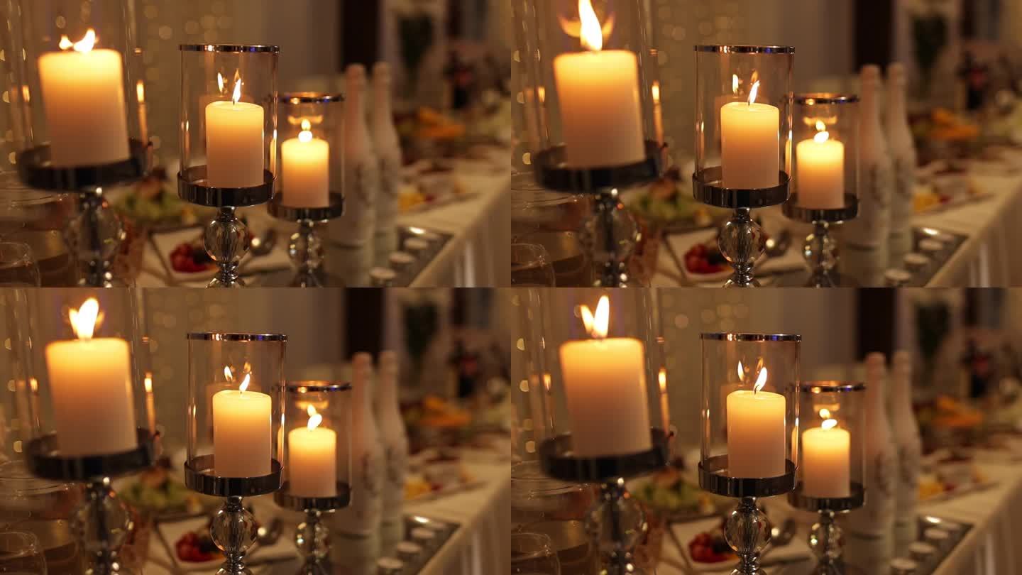 宴会厅内部豪华细节。在黑暗的房间里，婚礼桌上的玻璃和水晶烛台上燃烧着蜡烛和烧瓶。浪漫的气氛在晚上或晚