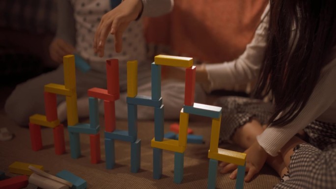 两个孩子在房间里玩积木的画像。活跃的韩国兄弟姐妹，花时间在一起，合作建造一个多彩的木制城堡