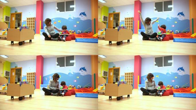 在幼儿园的室内，女老师正在和一个坐在那里看书的孩子玩耍