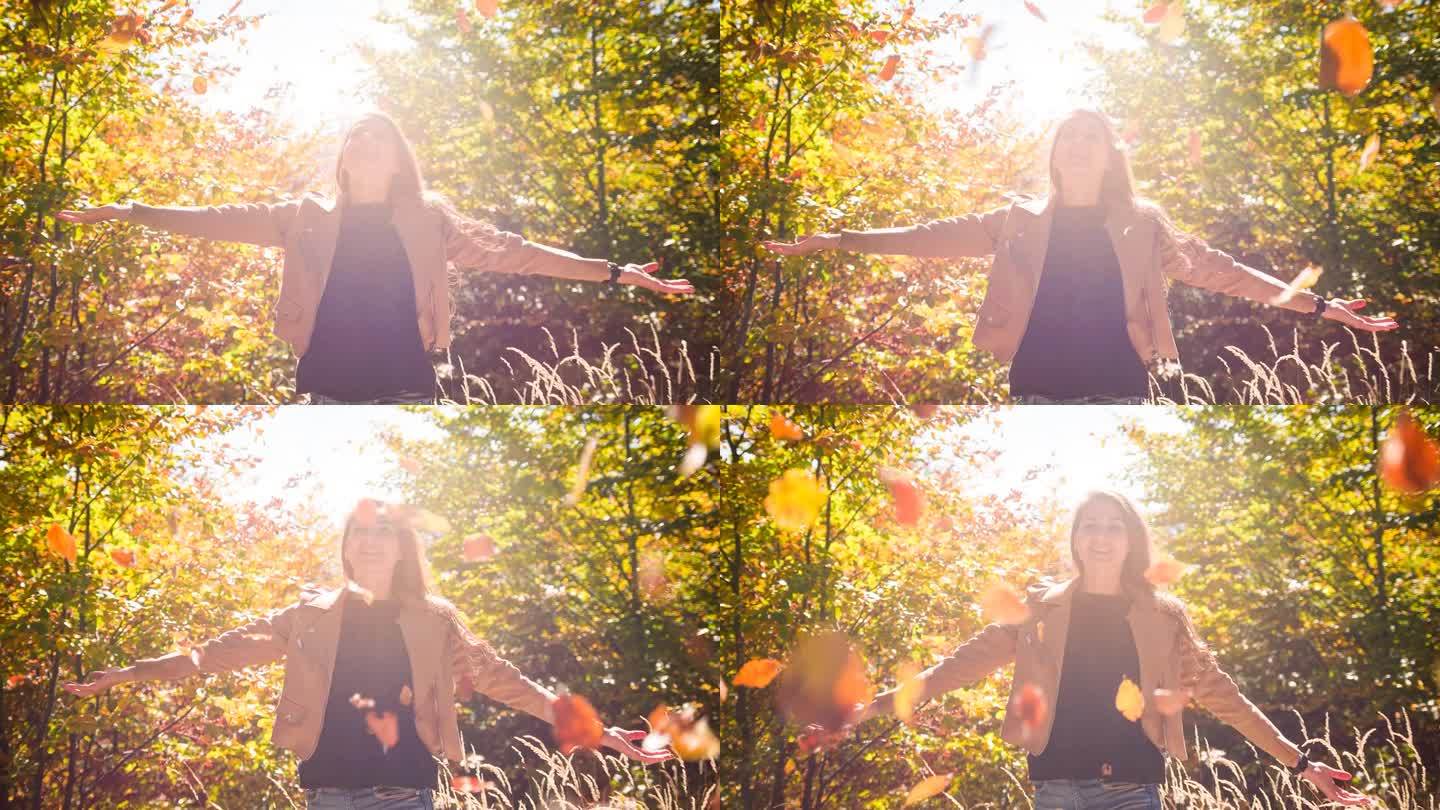 阳光照耀着一个快乐的女人，她把五彩缤纷的秋叶抛向空中