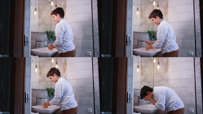 个人卫生，可爱的少年站在浴室水槽旁，用肥皂洗手，用水冲洗掉泡沫