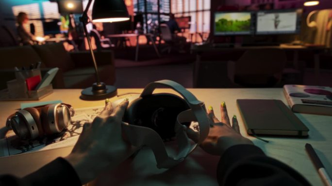 一个人在创意办公室拿起并戴上虚拟现实耳机的场景。模拟插入自己的VFX虚拟现实3D宇宙，数字办公界面，