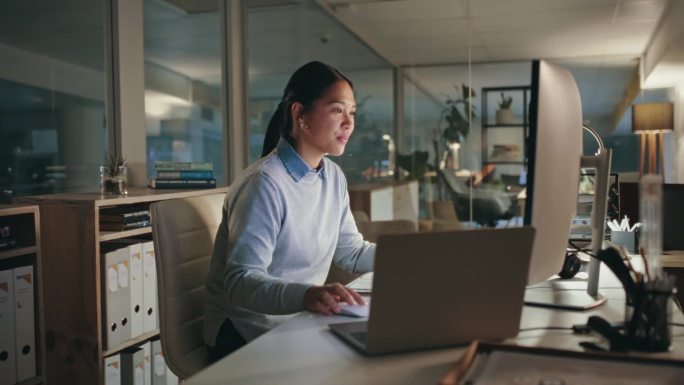 网页设计，电脑和女人晚上在办公室做一个有截止日期的项目。技术、加班和年轻的亚洲女性开发人员在一个在线