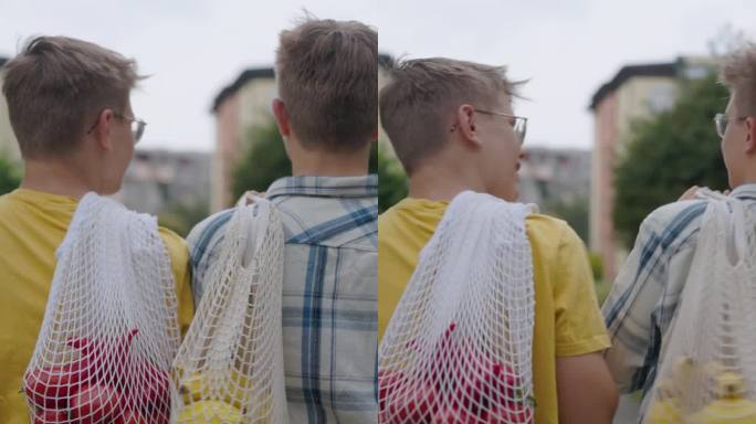 两个十几岁的男孩用可重复使用的购物袋把杂货带回家