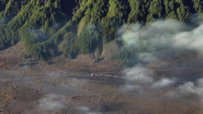 空中无人驾驶吉普车在印度尼西亚爪哇岛东爪哇岛的布罗莫山周围旅行，岩石与火山岩和沙丘为背景