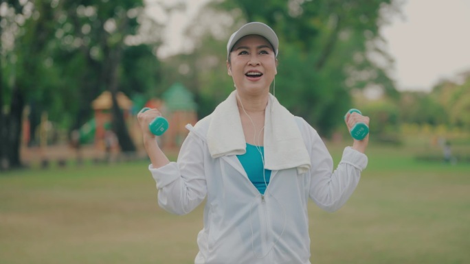 亚洲成熟女性用哑铃锻炼，为健康的生活方式增强力量和信心