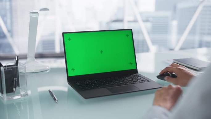在笔记本电脑上工作的匿名人士与绿屏模拟Chromakey。商人使用鼠标，浏览互联网，分析公司项目计划